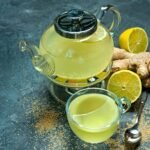 lemon tea benefits in a cup with sliced lemon and herbs